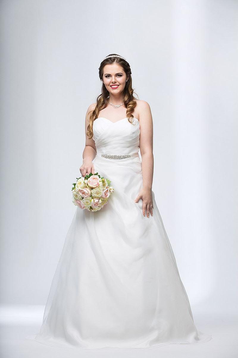 Lächelnde Curvy Braut in einem Brautkleid in großer Größe