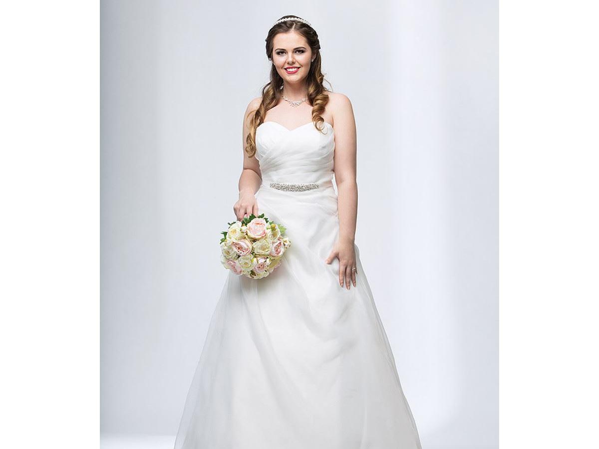 Lächelnde Curvy Braut in einem Brautkleid in großer Größe