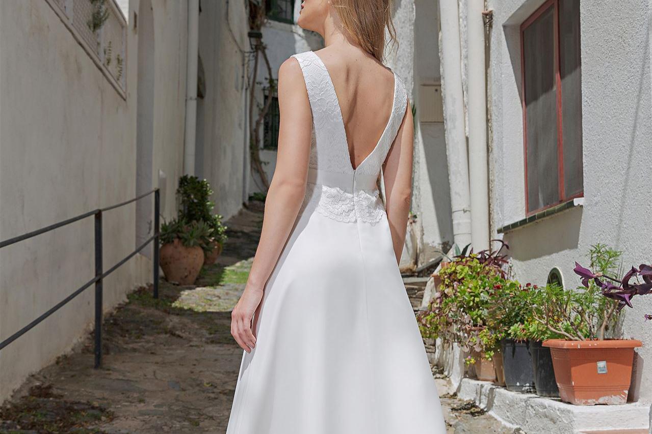 Eine Frau in einem weißen Hochzeitskleid steht in einer engen, mediterran anmutenden Altstadtgasse.