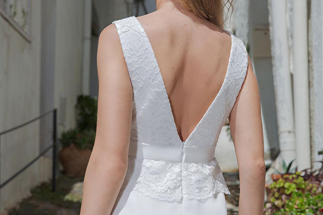 Blonde Frau im weißen Kleid, die von hinten in einem historischen Hof zu sehen ist.