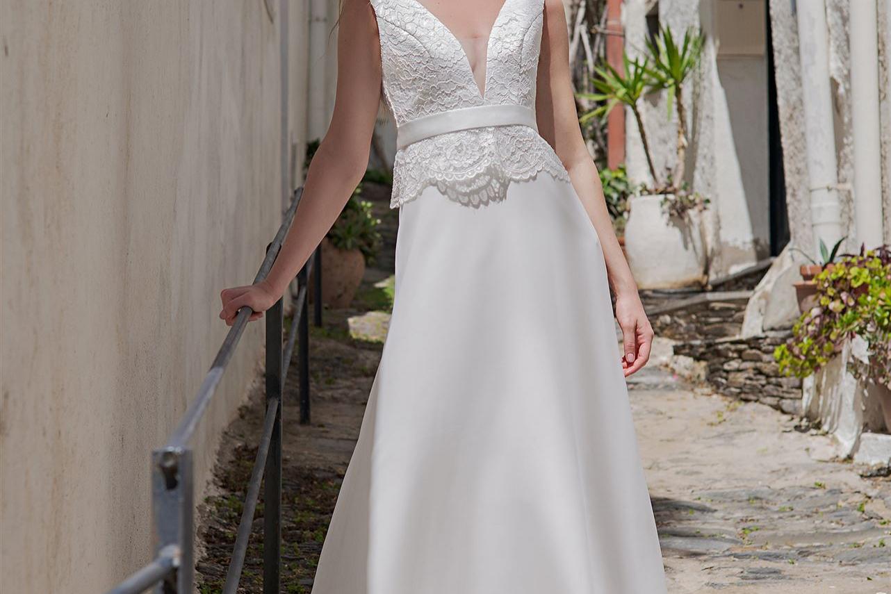 Eine junge Frau in einem eleganten weißen Kleid blickt in eine historische Gasse.