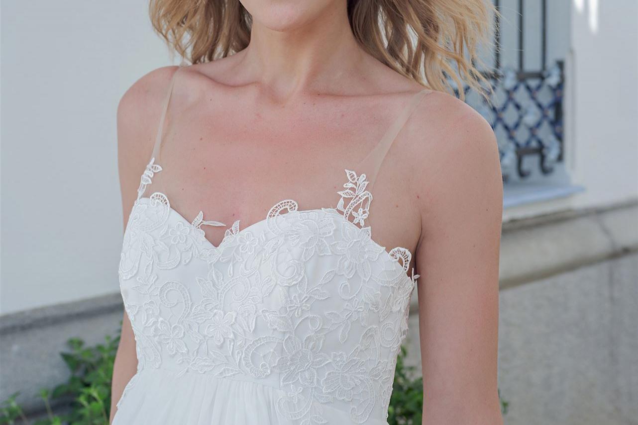 Blonde Frau in einem weißen Kleid, die in einem hellen, sommerlichen Ambiente posiert.