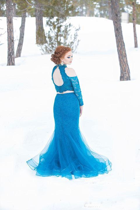 Braut in blauem Brautkleid mit Langarm aus Spitze steht in winterlicher Kulisse