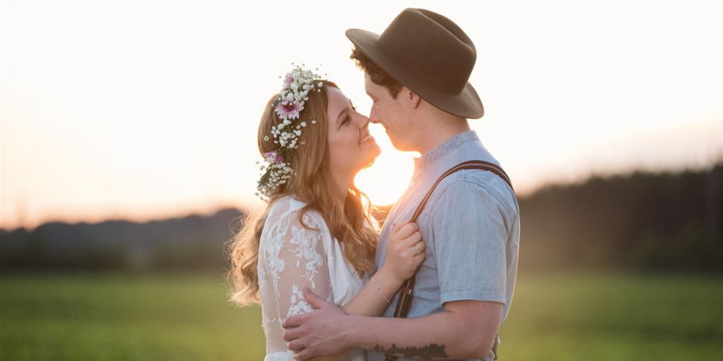 Eine junge Braut und ein Bräutigam mit Hut vor dem Horizont