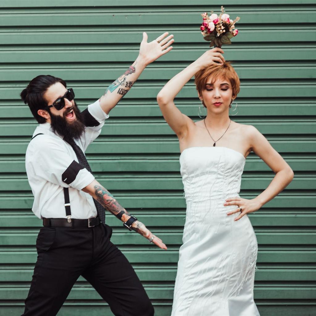 Junges Brautpaar vor grüner Wand in frecher Pose