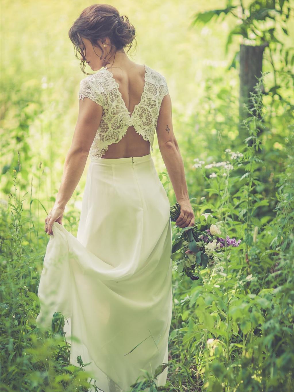 Braut im zweiteiligen rückenfreien Kleid in der Natur